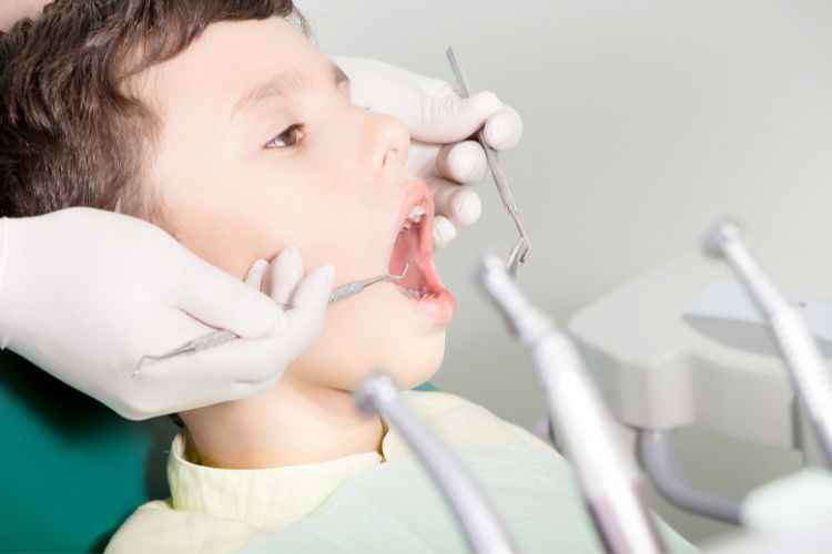niño con dientes de leche de 6 años revisando su salud oral